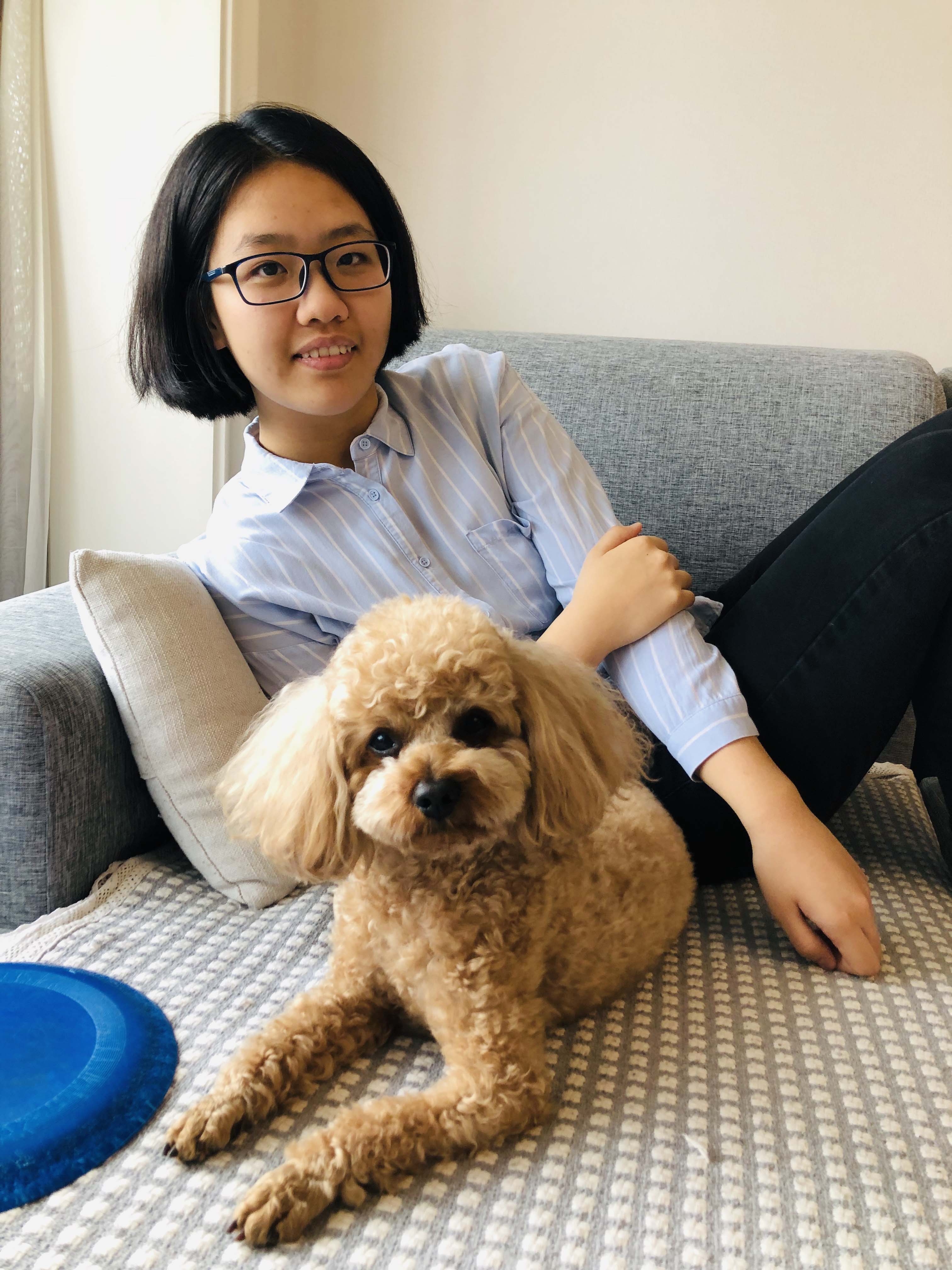 Isabella Han smiling for the camera with her small dog, named Ketchup, who is also facing the camera and smiling.