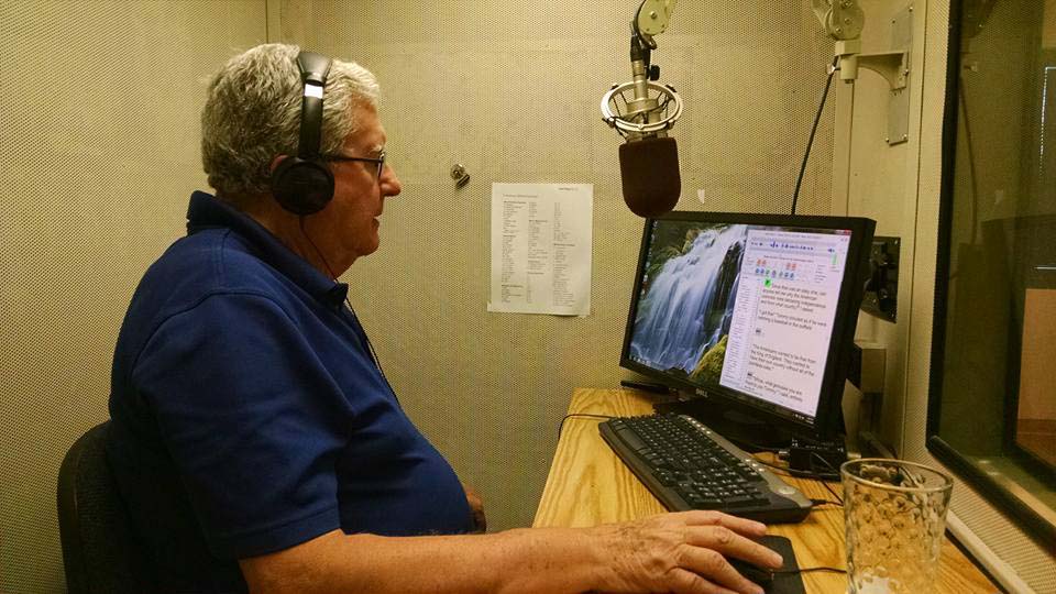Jim sitting in a recording booth reading